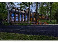 Stunning stone home with modern design elements surrounded by mature trees, creating a private and picturesque setting at 12469 Springmill Rd, Carmel, IN 46032