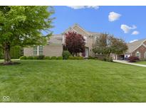 Beautiful two-story brick home featuring a lush green lawn and charming landscaping at 14094 Pecos Ct, Carmel, IN 46033