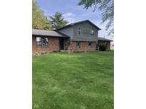 Charming two-story home with a brick facade and a spacious front yard, complemented by a rustic wooden fence at 21749 Oak Ridge Rd, Sheridan, IN 46069