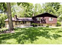 A charming exterior of a home with stone and wood siding, surrounded by lush greenery and mature trees at 6248 Graham Rd, Indianapolis, IN 46220