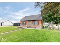 Charming single-story home featuring orange siding, a stone chimney, and a spacious front lawn with a playground at 671 W 350 N, Shelbyville, IN 46176