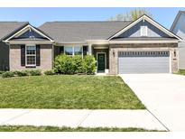 Charming single-story brick home with a well-manicured lawn, lush shrubs, and a gray two-car garage at 6832 Oakcrest Dr, McCordsville, IN 46055