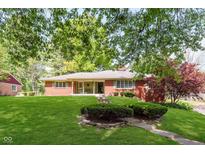 Charming single-story brick home with a well-manicured lawn and mature trees at 7135 Huntington Rd, Indianapolis, IN 46240