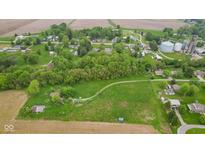 An aerial view of the land, revealing a large parcel with a road leading towards trees and a cluster of houses at 8293 Water St, Coatesville, IN 46121