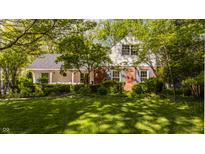Charming two-story home featuring a brick facade, white trim, blue shutters, and a well-manicured lawn with mature trees at 8770 N Pennsylvania St, Indianapolis, IN 46240