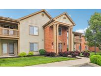 Inviting condominium exterior with manicured lawn, beautiful shrubs, and brick entryway at 8910 Hunters Creek Dr # 207, Indianapolis, IN 46227