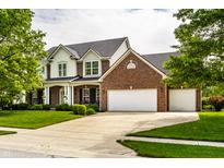 Stunning two-story brick home featuring a three-car garage, manicured lawn and mature trees at 14805 Chamberlain Dr, Westfield, IN 46074
