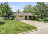 Ranch style home with attached two-car garage, mature trees, and a large front lawn at 1817 Edgewood Dr, Anderson, IN 46011