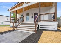 Close-up of a charming covered front porch with wood railings and a modern entrance at 1825 E Maryland St, Indianapolis, IN 46201
