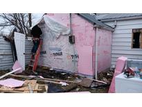 Ongoing home renovations with worker on ladder, Typar paper, and building materials scattered around at 4106 N Pasadena Ave, Indianapolis, IN 46226