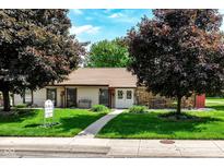 Charming single-story home with a well-manicured lawn and mature trees under a brilliant blue sky at 4504 Harvard Dr, Anderson, IN 46013