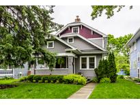 Charming home featuring grey siding, lush lawn, mature trees, and a covered front porch at 5015 N Park Ave, Indianapolis, IN 46205
