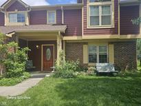 Charming townhouse featuring a covered porch, brick accents, and well-manicured front yard at 6723 Silver Tree Dr, Indianapolis, IN 46236