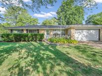 Charming one-story brick home featuring an attached garage and lush front yard landscaping at 726 Coach Rd, Indianapolis, IN 46227