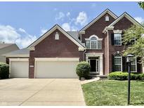 A charming two-story brick home featuring a manicured lawn and an attached three-car garage at 12044 Bird Key Blvd, Fishers, IN 46037
