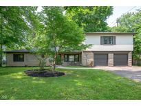 Charming two-story home featuring a stone facade and a well-maintained front yard with mature trees at 2120 Wynnedale Rd, Indianapolis, IN 46228