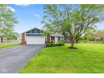 Charming home with a blue facade, brick accents, well-manicured lawn, and a mature shade tree enhancing curb appeal at 2309 Alexandria Dr, Greenfield, IN 46140