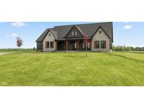 Charming stone and dark siding farmhouse with large front yard and beautiful landscaping at 4457 E County Road 850 N, Pittsboro, IN 46167