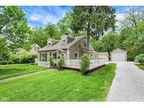 A charming two-story home is nestled in a lush green setting, complete with a gravel driveway and detached garage at 5104 Carvel Ave, Indianapolis, IN 46205