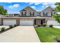 Charming townhome with a two-car garage, gray siding, brick accents, and a well-manicured lawn at 6463 Wasco Dr, Whitestown, IN 46075