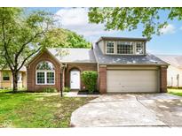 Charming brick home featuring a two-car garage, arched window, and inviting front entrance, complete with lush landscaping at 6471 Hunters Green Pl, Indianapolis, IN 46278