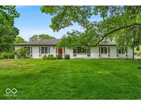 Charming ranch-style home featuring a well-manicured lawn and a welcoming red front door at 7316 Lesley Ave, Indianapolis, IN 46250