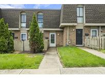 Charming townhome featuring brick facade, well-manicured lawn, and inviting entryway with tree at 7334 Country Brook Dr, Indianapolis, IN 46260