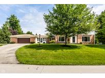 Beautiful brick home featuring an attached garage, a well-manicured lawn and a large tree in the front yard at 100 Wellington Rd, Indianapolis, IN 46260