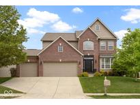 Inviting two-story brick home featuring a three car garage and well-manicured lawn at 11872 Traymoore Dr, Fishers, IN 46038