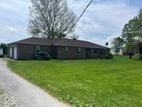 Spacious single-story brick home featuring a large lawn, mature trees, and attached two-car garage at 1925 W State Road 32, Lebanon, IN 46052