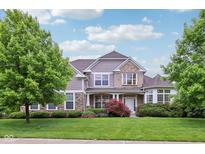 Charming two-story home featuring stone and siding exterior with manicured lawn and lush landscaping at 3744 Abney Point Dr, Carmel, IN 46077