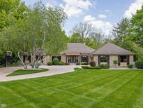 Stunning stone home featuring well-manicured lawn, mature trees, and circular driveway at 470 Mill Farm Rd, Noblesville, IN 46062