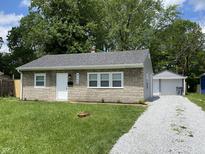 Charming single-story home featuring stone accents, a white front door, and a detached garage at 6150 E 25Th St, Indianapolis, IN 46219