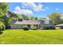 Charming ranch-style house featuring a lush lawn, mature trees, and manicured landscaping at 7035 Creekside Ln, Indianapolis, IN 46220