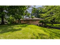Well-maintained one-story home with brick facade, mature trees, and green lawn at 7887 Meadowbrook Dr, Indianapolis, IN 46240