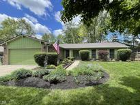 Charming one-story home with a green garage door, beautiful landscaping, and an American flag at 8206 Bull Run Ct, Indianapolis, IN 46227