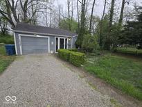 Charming one-story home with gray siding, lovely greenery, and an extended gravel driveway at 1212 River Heights Dr, Indianapolis, IN 46240