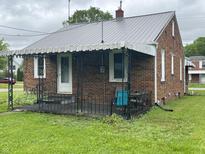Charming brick home featuring a metal roof and a cozy covered front porch at 1739 Crystal St, Anderson, IN 46012