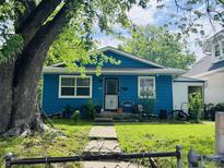 Charming blue home featuring a well-maintained lawn, sidewalk, and mature shade tree at 1809 N Harding St, Indianapolis, IN 46202