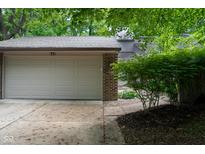 Attached two-car garage featuring a gray door and brick siding with lush greenery at 35 Osage Ct, Columbus, IN 47201