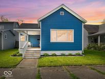 Charming blue two-story home with a quaint front porch and well-maintained lawn at dusk at 547 W Taylor St, Shelbyville, IN 46176