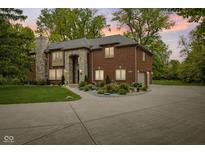 Stately brick home with stone accents, manicured landscaping, and a circular driveway at 6230 E 56Th St, Indianapolis, IN 46226