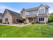 Elegant two-story home featuring brick and siding exterior, complemented by a lush green lawn and mature landscaping at 12082 Old Stone Dr, Indianapolis, IN 46236
