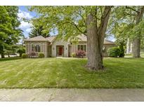 Charming home featuring a stone facade, red door, manicured lawn and mature trees at 1941 Orchard Ct, Carmel, IN 46280