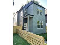 Two-story home with green siding, a modern front door, and a well-maintained lawn and wooden fence at 39 N Walcott St, Indianapolis, IN 46201