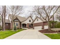 Beautiful brick home with a manicured lawn, mature trees, and a spacious driveway at 4037 Oakleaf Dr, Zionsville, IN 46077