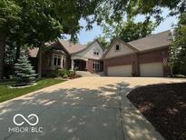 Brick home featuring an attached two-car garage, manicured lawn, and a long driveway at 4037 Oakleaf Dr, Zionsville, IN 46077