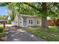 Cozy home featuring light gray siding, an inviting entryway, and a mature tree shading the property at 4809 Allisonville Rd, Indianapolis, IN 46205