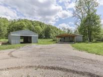 Wide driveway leading to a metal garage and a house with covered parking, surrounded by lush greenery at 6091 Mt Moriah Rd, Nineveh, IN 46164