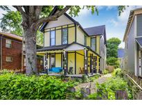 Charming yellow two-story home with inviting front porch and beautiful landscaping at 847 N Park Ave, Indianapolis, IN 46202